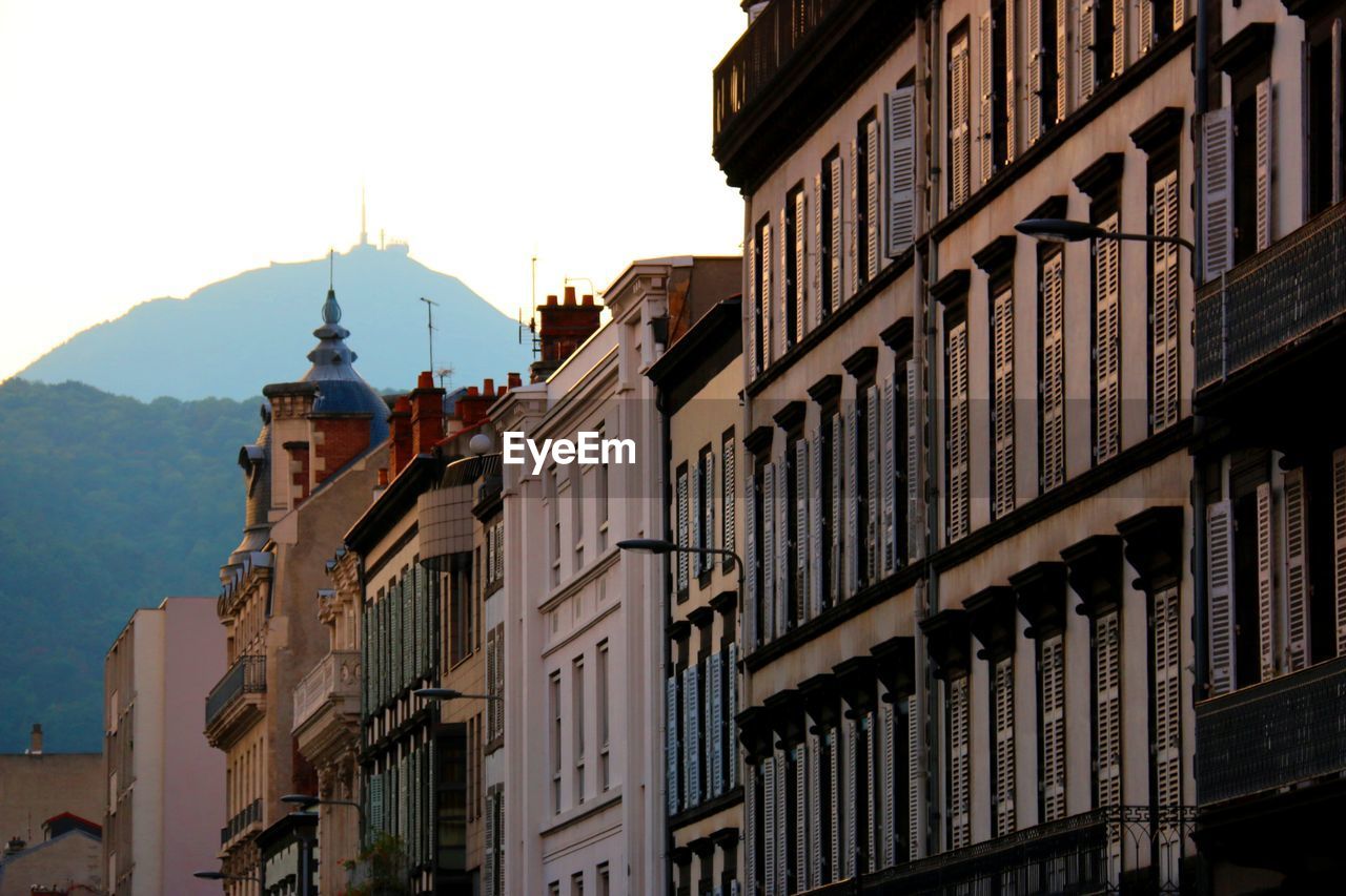 Low angle view of buildings against mountain and sky