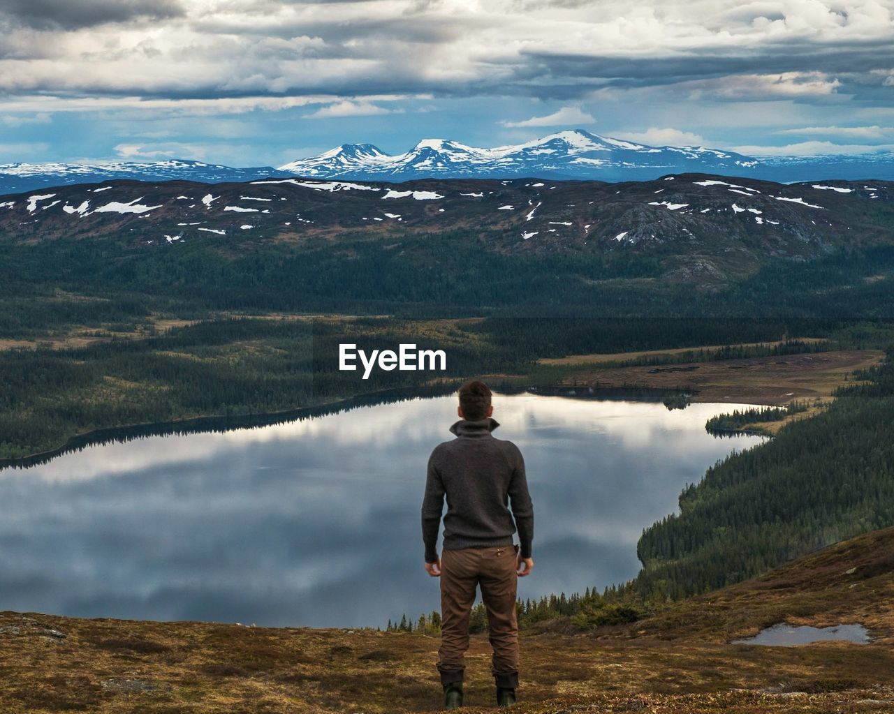 Rear view of man standing on mountain by lake