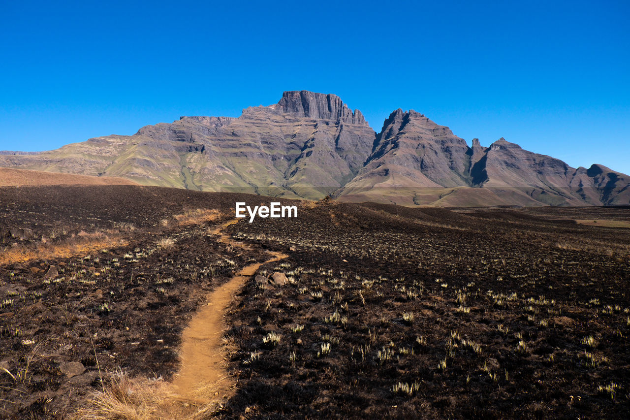 Scenic view of land and mountains against clear blue sky