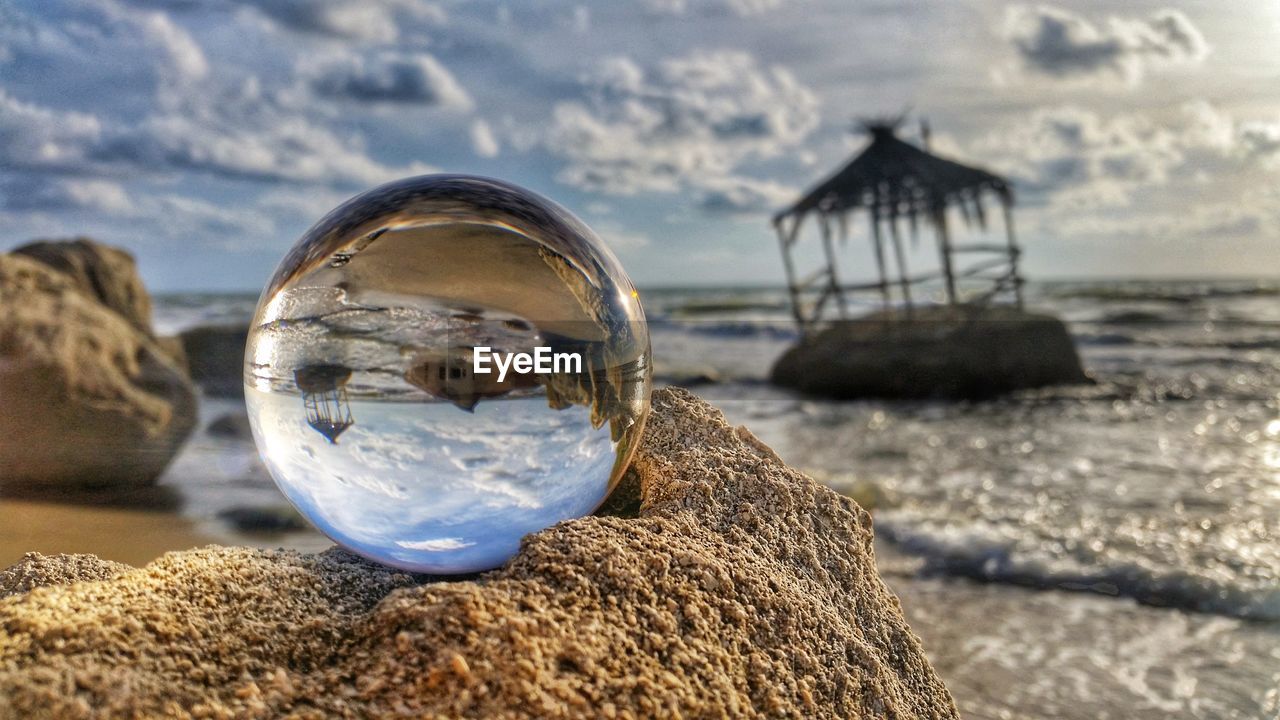 CLOSE-UP OF CRYSTAL BALL ON BEACH AGAINST SEA