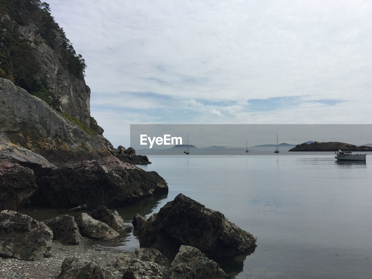 Rocky shore against cloudy sky