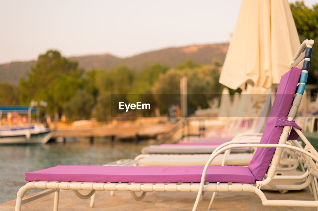 Lounge chairs on pier by sea