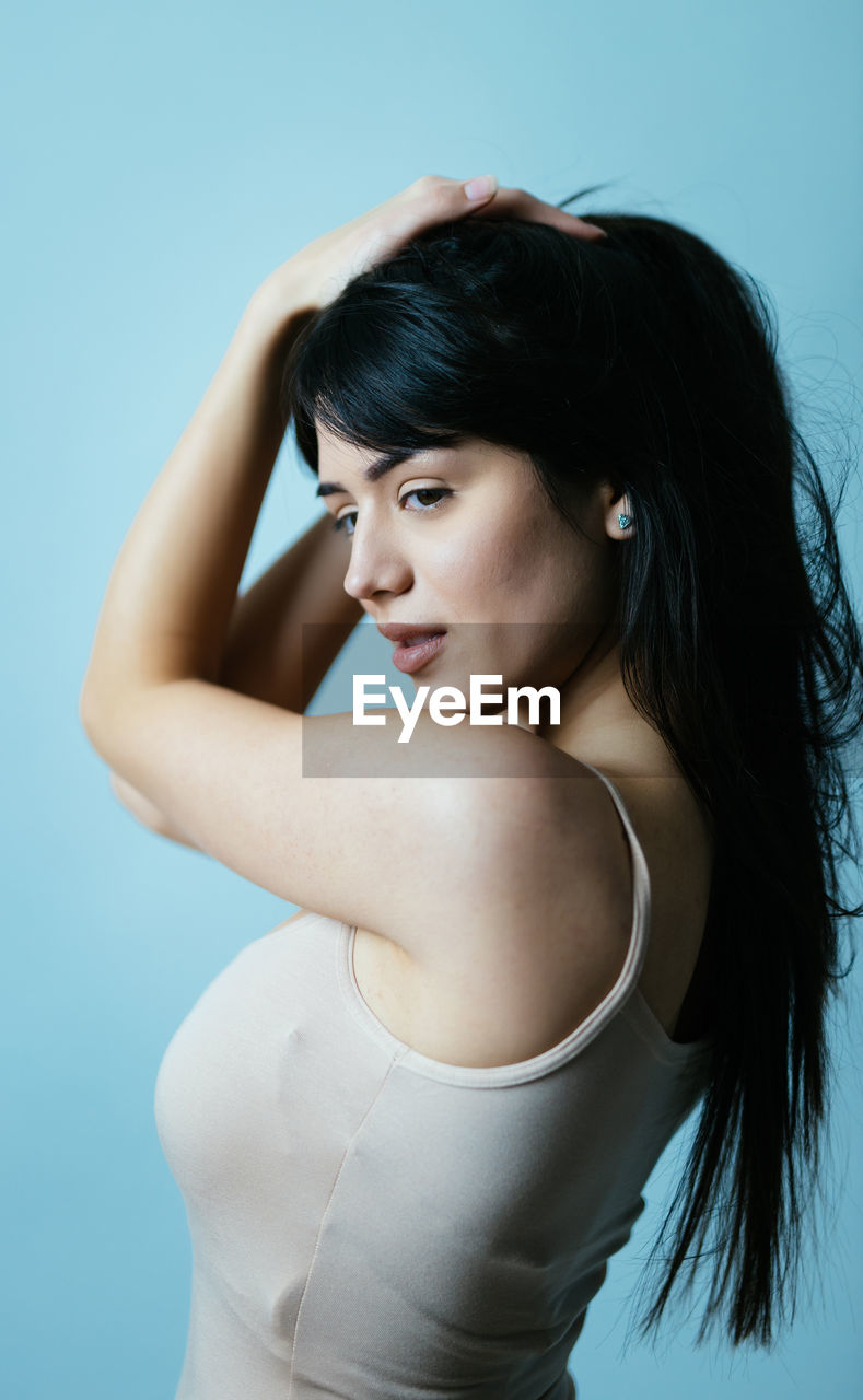 Young woman standing against blue background