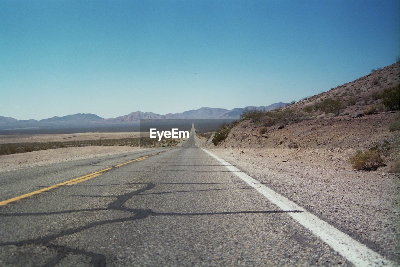 EMPTY ROAD LEADING TOWARDS MOUNTAINS