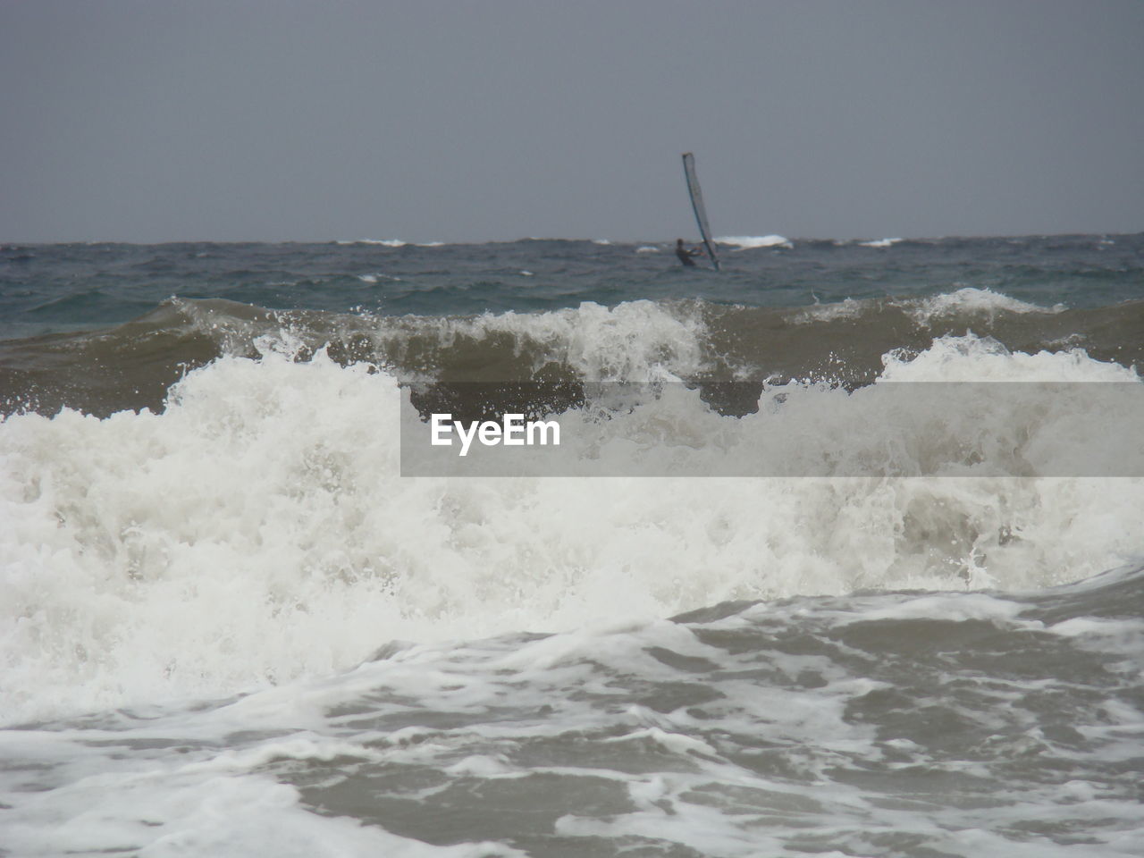 SCENIC VIEW OF SEA WAVES SPLASHING ON SHORE AGAINST SKY