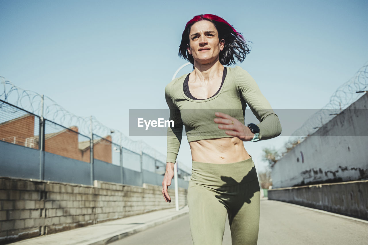 Woman running on road against blue sky