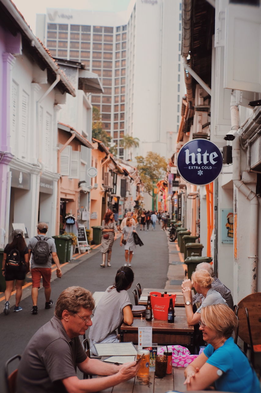 PEOPLE ON STREET BY BUILDINGS