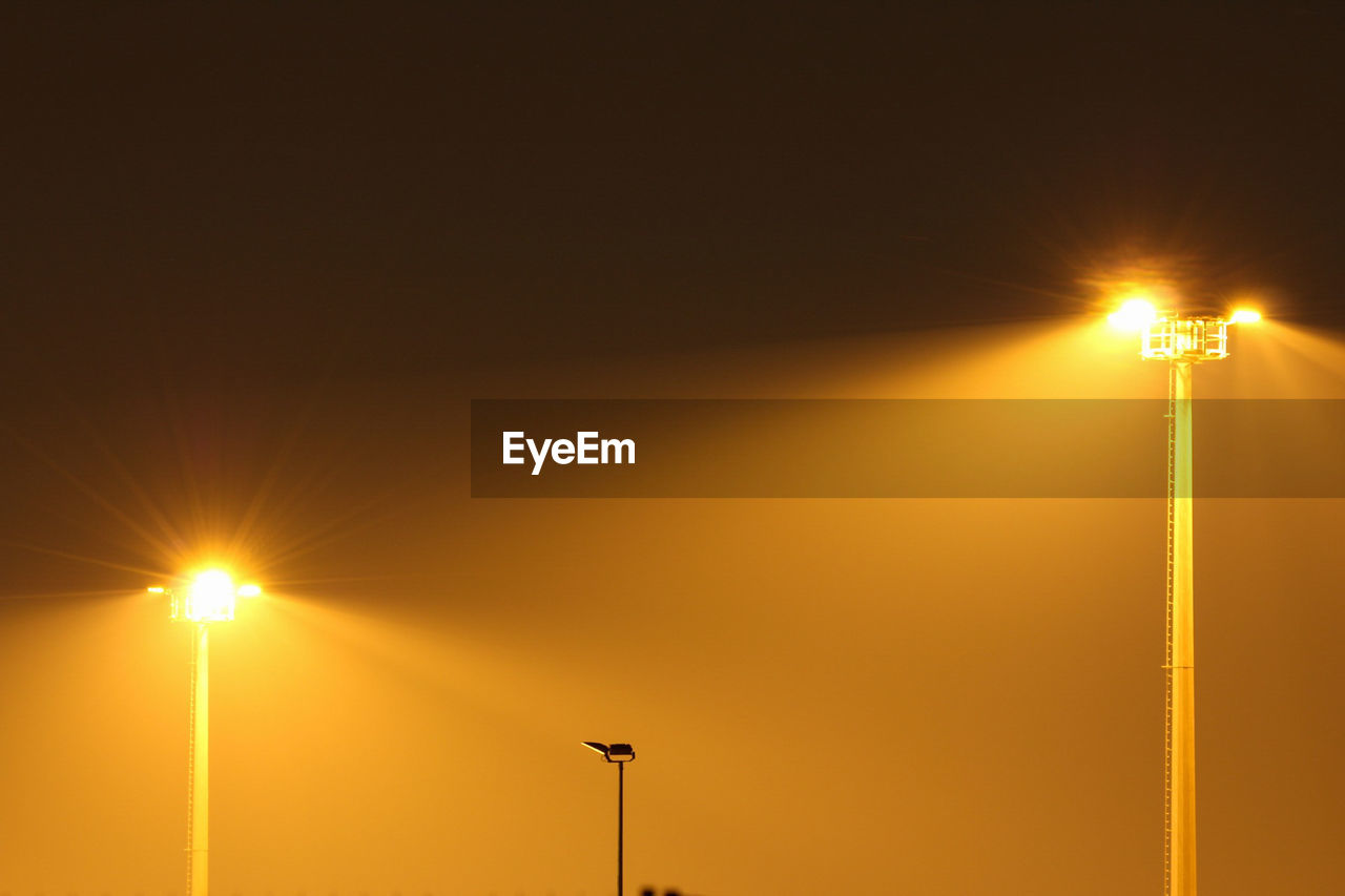 Low angle view of illuminated street lights against sky at night