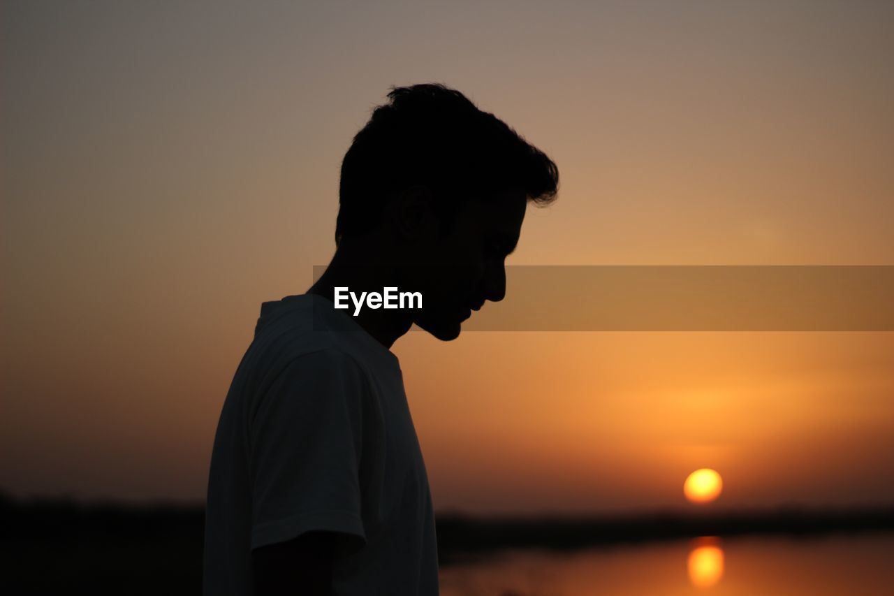 Silhouette man standing at beach during sunset