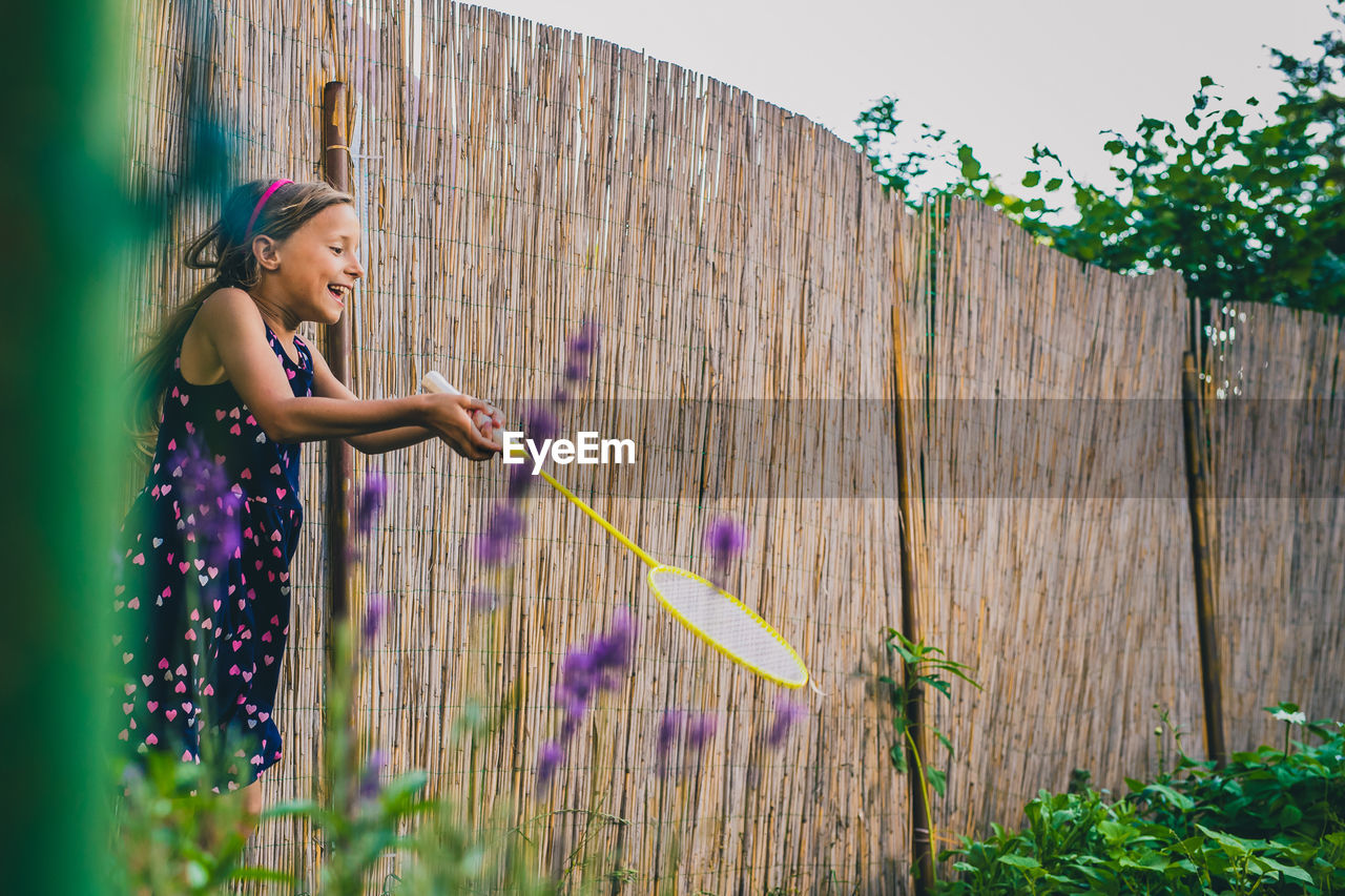 Side view of girl playing badminton in yard