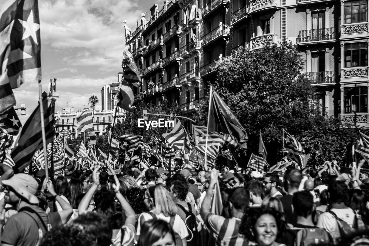 CROWD ON STREET AMIDST BUILDINGS