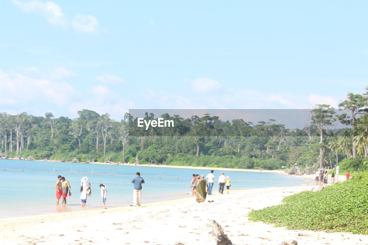 TOURISTS ON BEACH AGAINST SKY