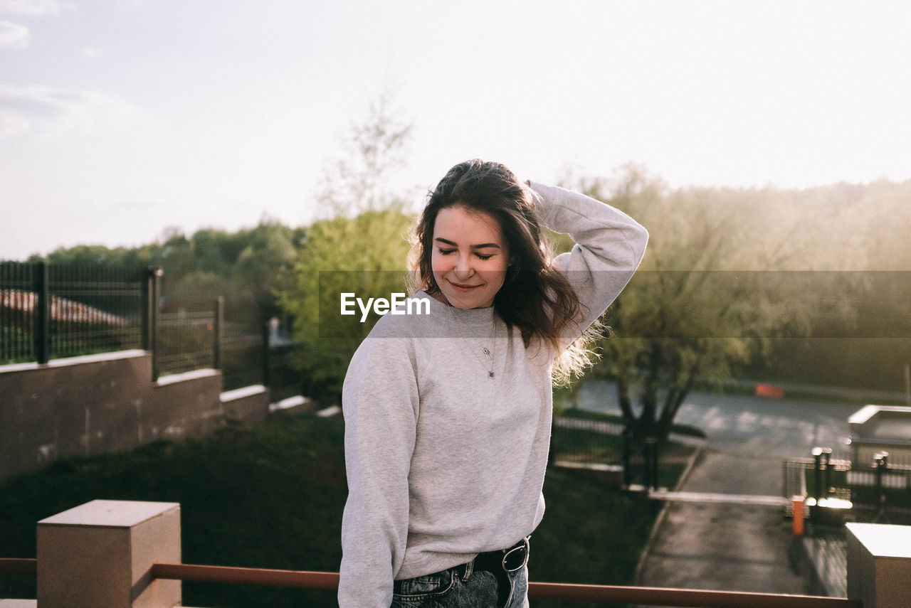 Smiling woman standing against trees