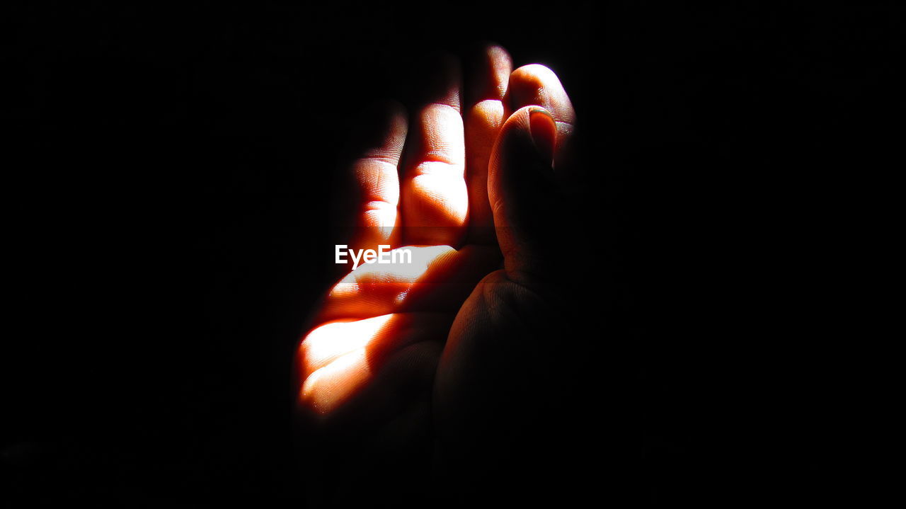 CLOSE-UP OF HUMAN HAND OVER BLACK BACKGROUND
