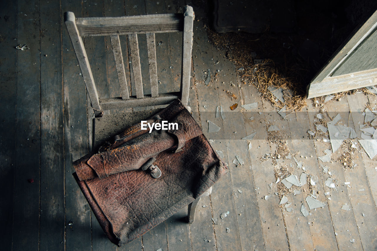 High angle view of old leather bag on chair in abandoned house