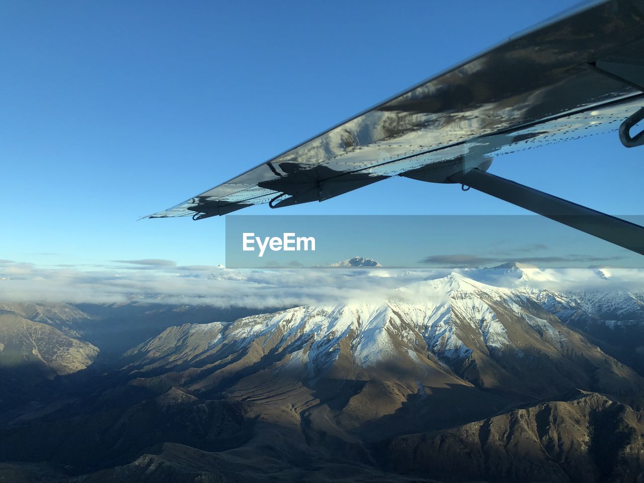Aerial view of snowcapped mountains against blue sky