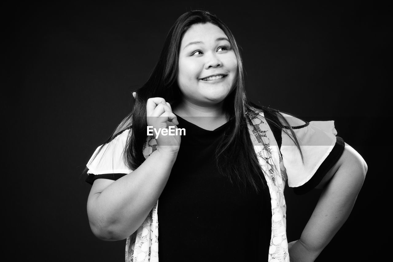 Portrait of smiling young woman against black background