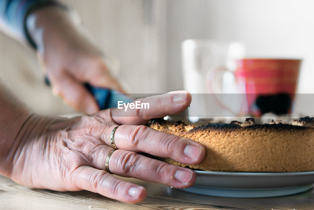 Close-up of hands cutting cake