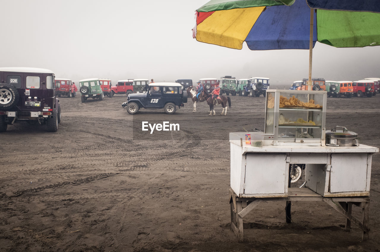 Food stall on field by cars during foggy weather