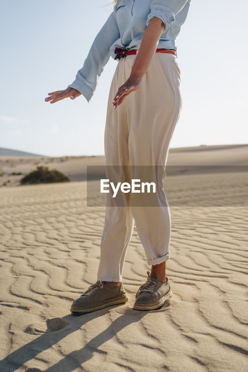 Low section of woman standing on sand