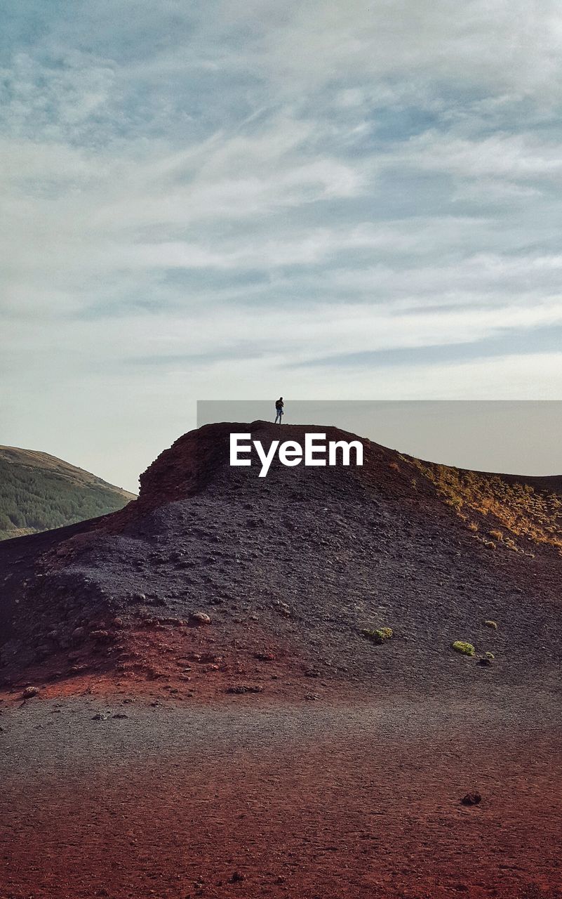 Person standing on mountain against sky