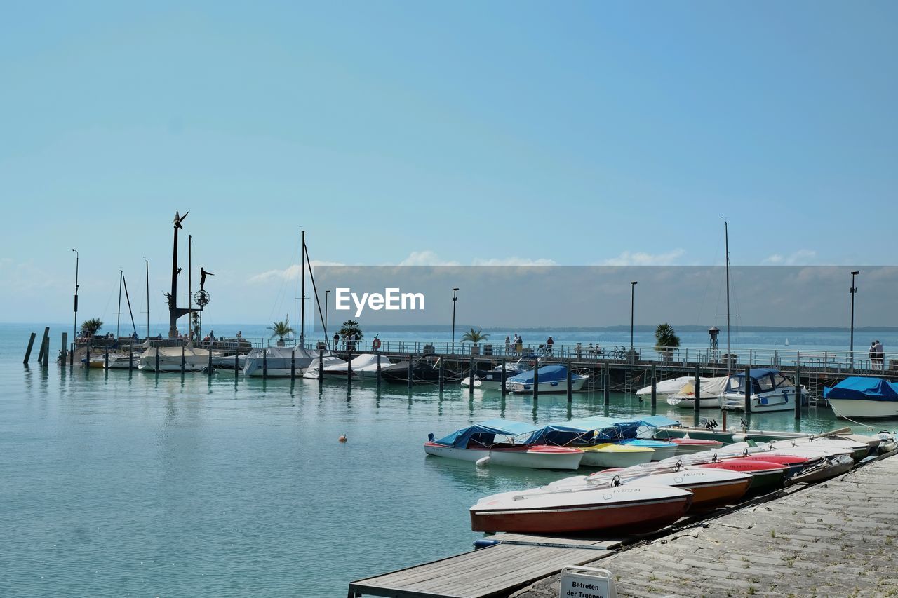 water, nautical vessel, transportation, marina, sky, sea, dock, mode of transportation, harbor, moored, nature, bay, boat, coast, pier, port, sailboat, no people, tranquility, vehicle, pole, day, blue, beach, mast, travel, shore, beauty in nature, travel destinations, clear sky, ship, tranquil scene, scenics - nature, architecture, outdoors, idyllic, ocean, watercraft, land, vacation, boating, cloud, reflection, copy space, sunlight, holiday, trip, commercial dock, sunny