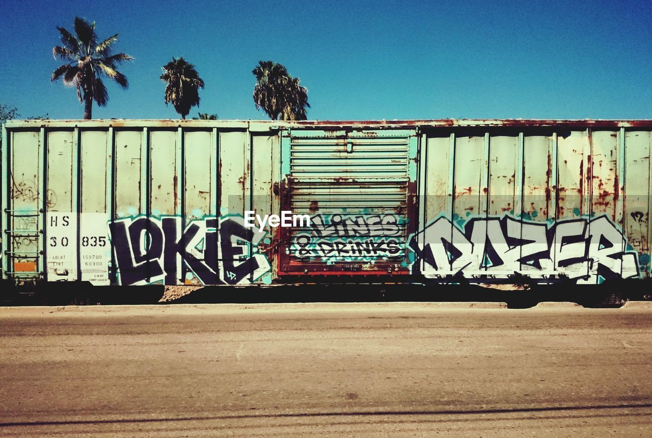 GRAFFITI ON BLUE ROAD AGAINST CLEAR SKY