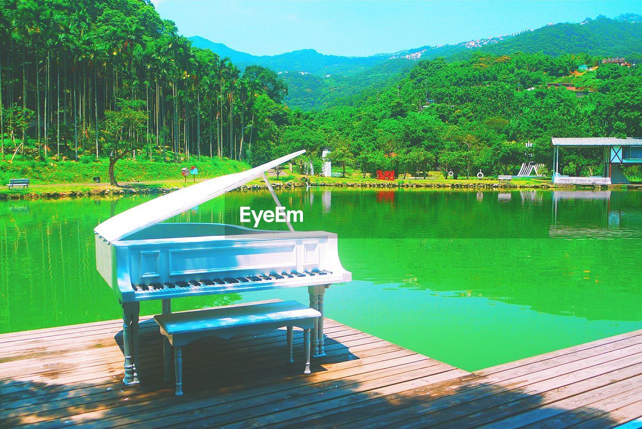 Grand piano on pier by lake