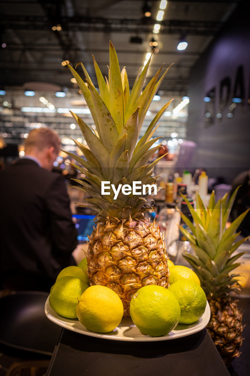 pineapple, ananas, fruit, food and drink, food, bromeliaceae, tropical fruit, healthy eating, plant, adult, freshness, citrus fruit, produce, business, yellow, indoors, wellbeing, floristry, retail, one person, lemon, men