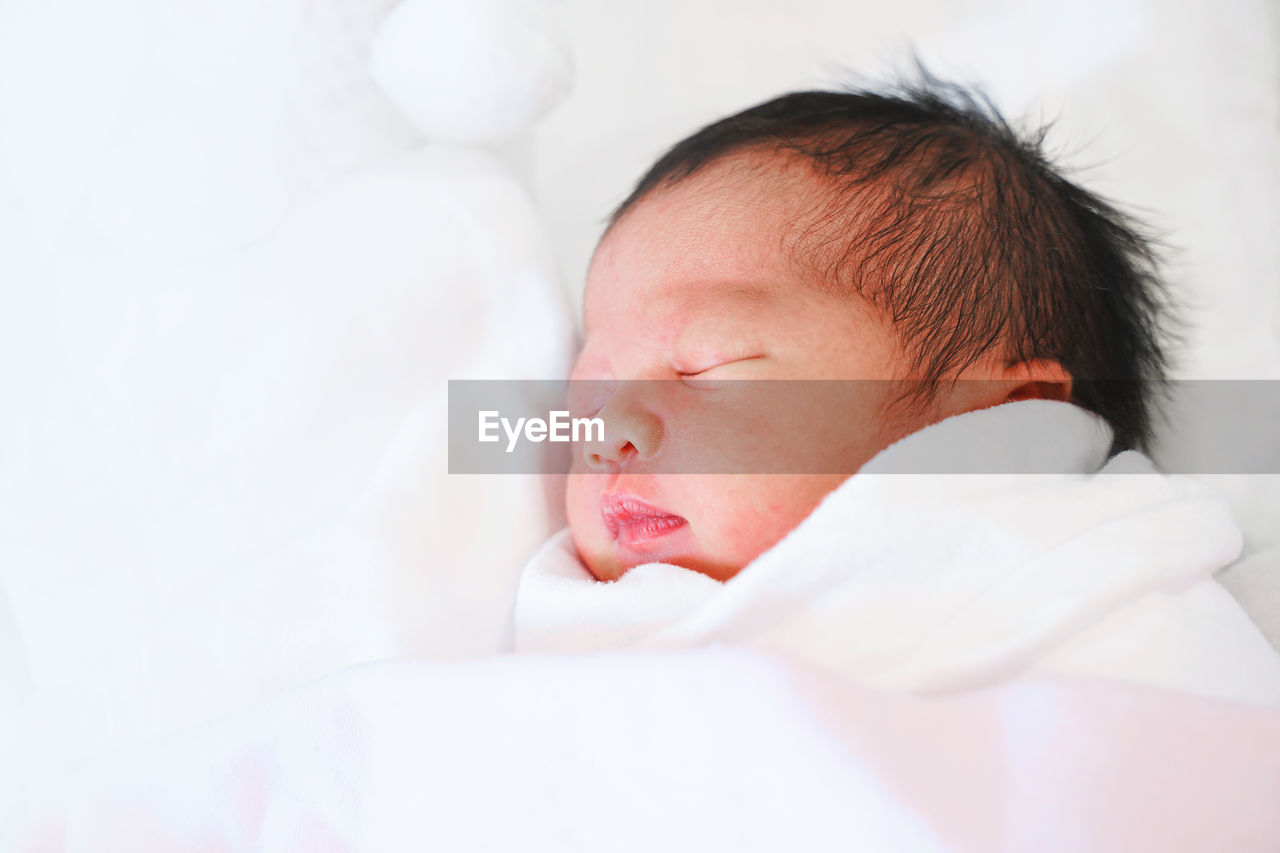 Close-up of cute baby girl sleeping on bed