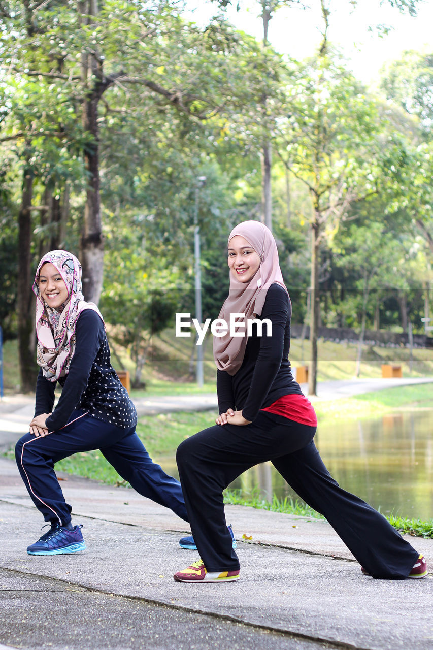 Sisters wearing hijab while exercising by lake at park