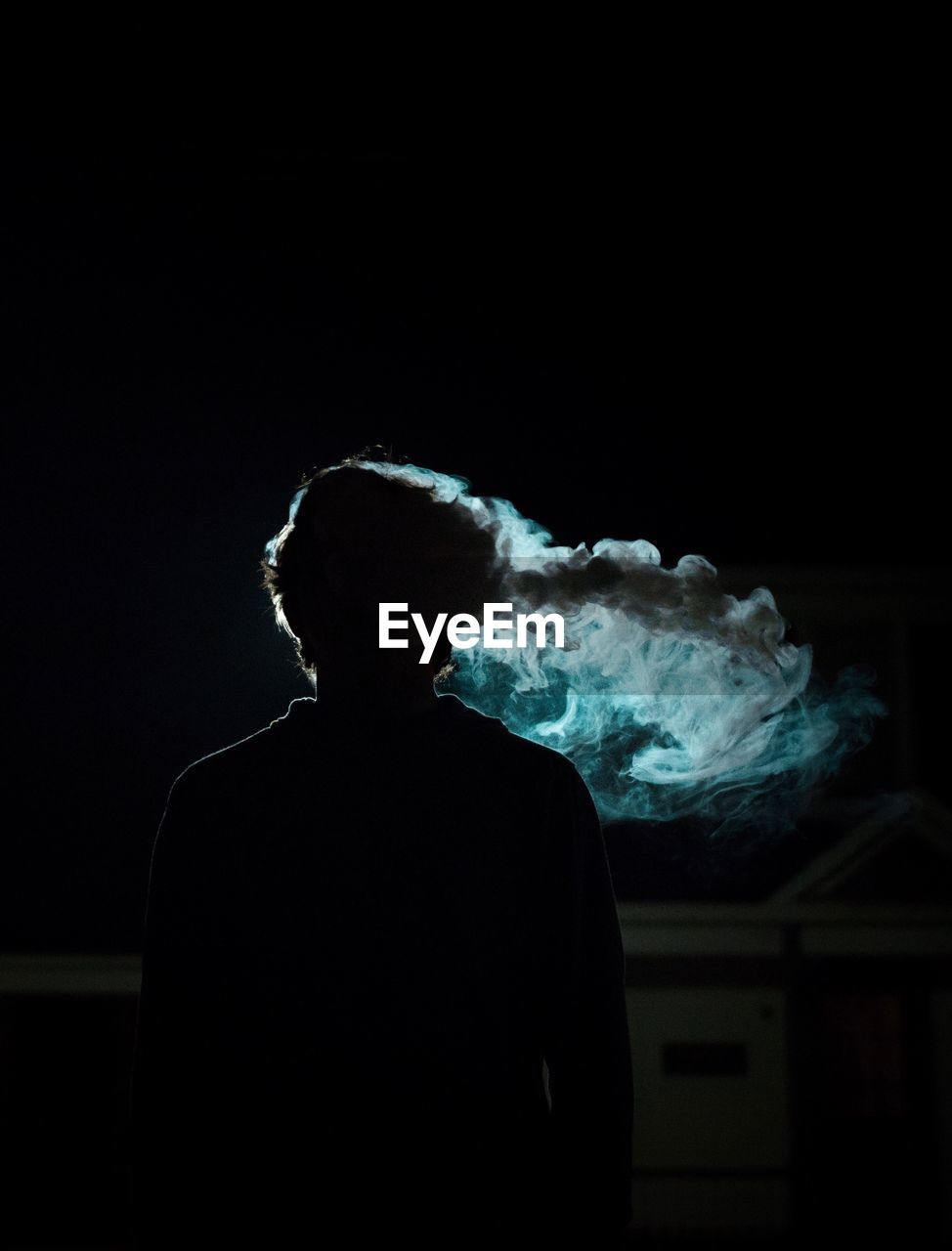 Silhouette man smoking at night