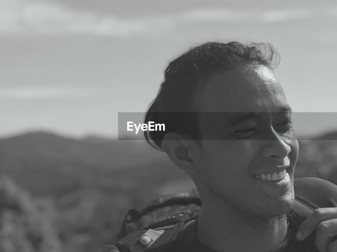 Close-up of smiling young man against sky