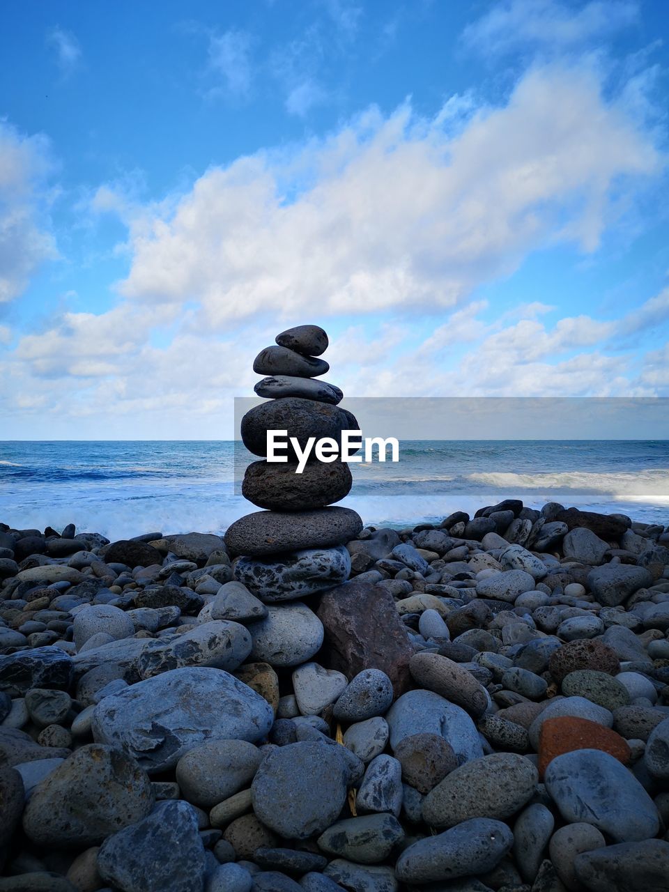 Stack of stones on beach against sky