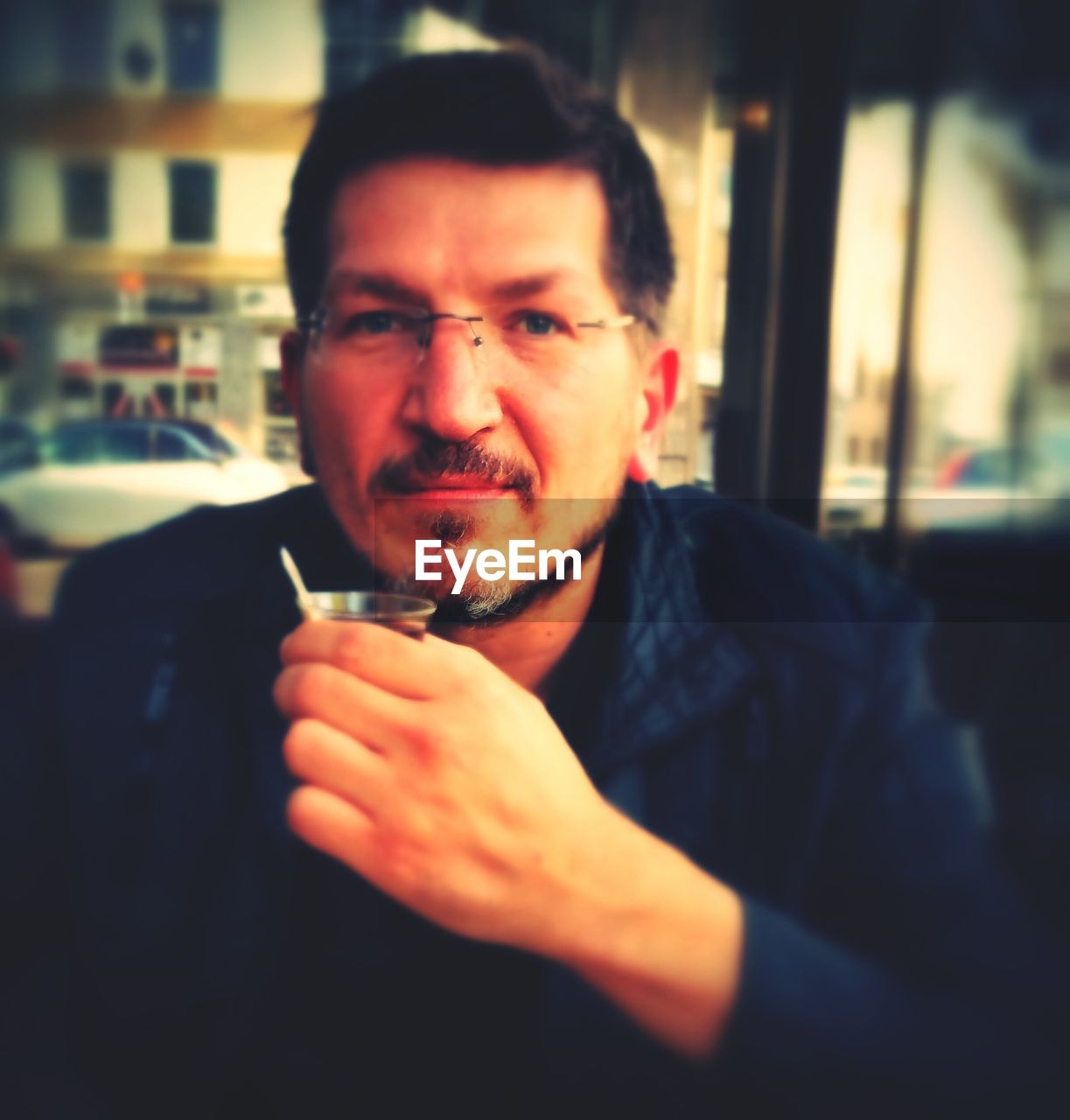 Portrait of confident man with drink at cafe