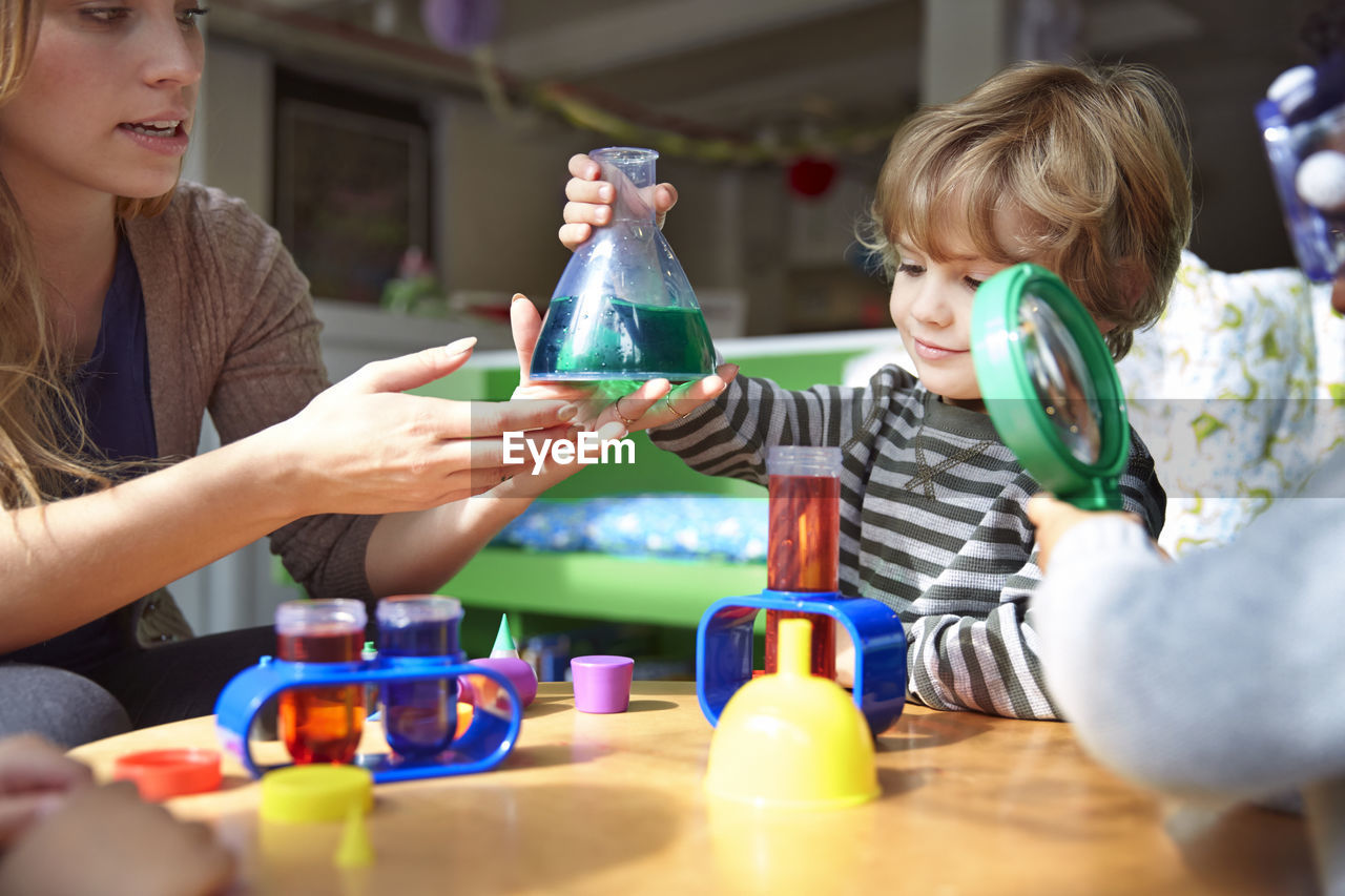 Teacher guiding students in doing science experiment at preschool