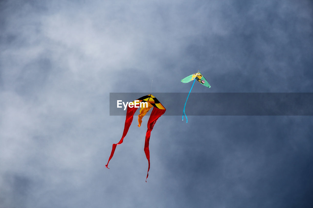 Low angle view of kites flying against sky