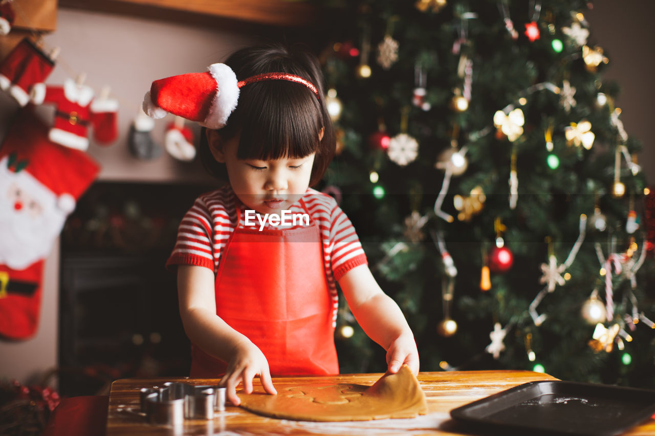 Girl making cookies at table during christmas