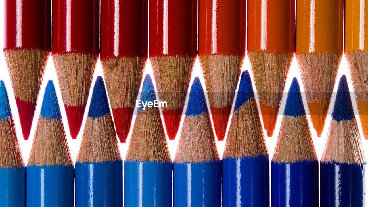 CLOSE-UP OF MULTI COLORED PENCILS AGAINST BLUE WALL