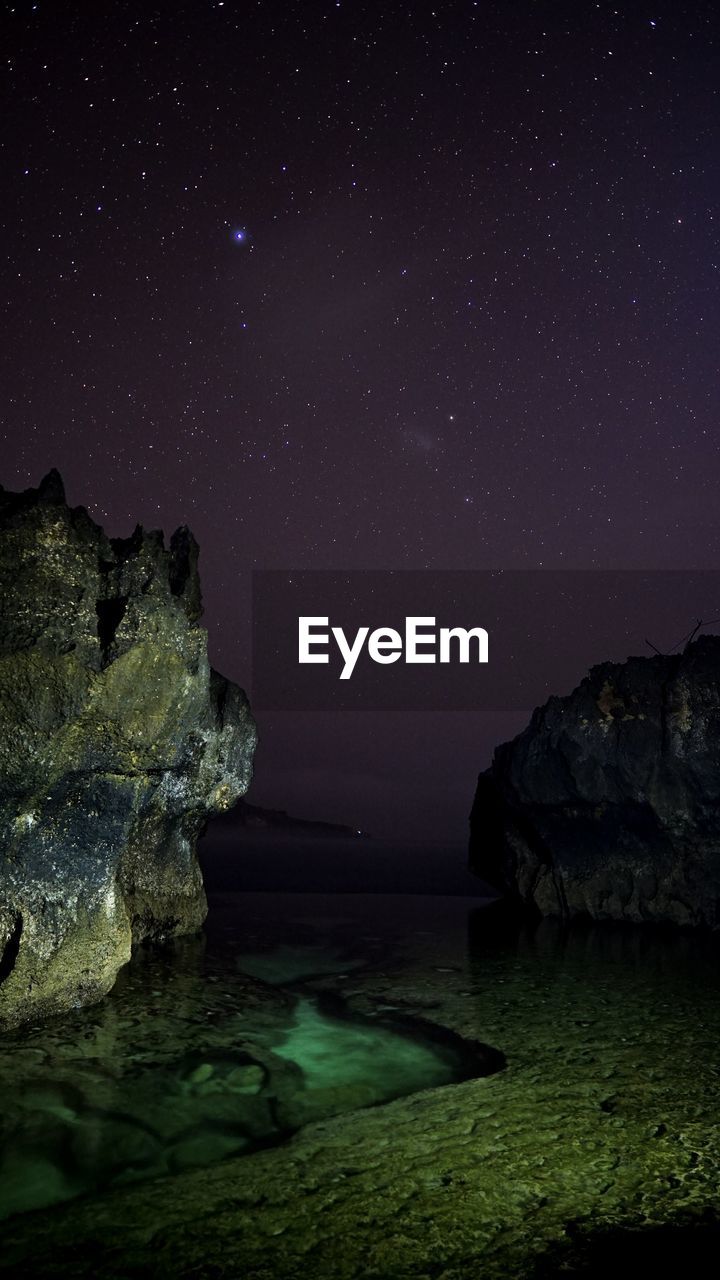 Scenic view of rock formation at angels billabong on nusa penida with beautiful night sky and stars 