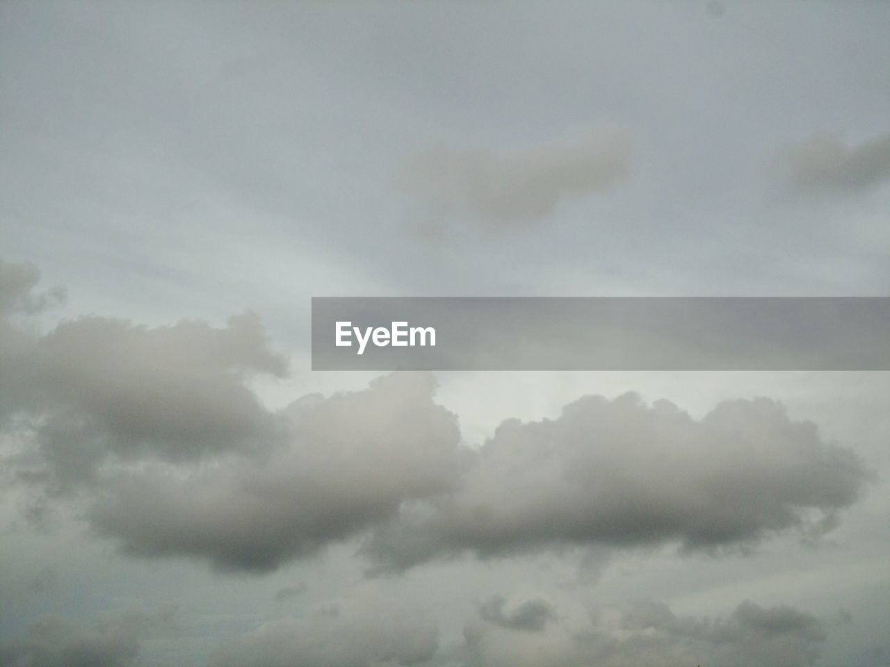 LOW ANGLE VIEW OF SUNLIGHT STREAMING THROUGH CLOUDS IN SKY