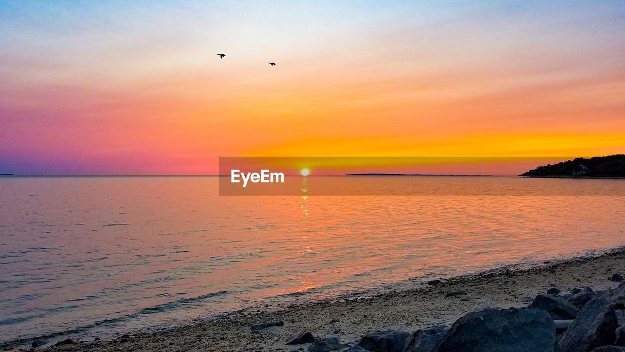 SCENIC VIEW OF SEA AGAINST ORANGE SKY DURING SUNSET