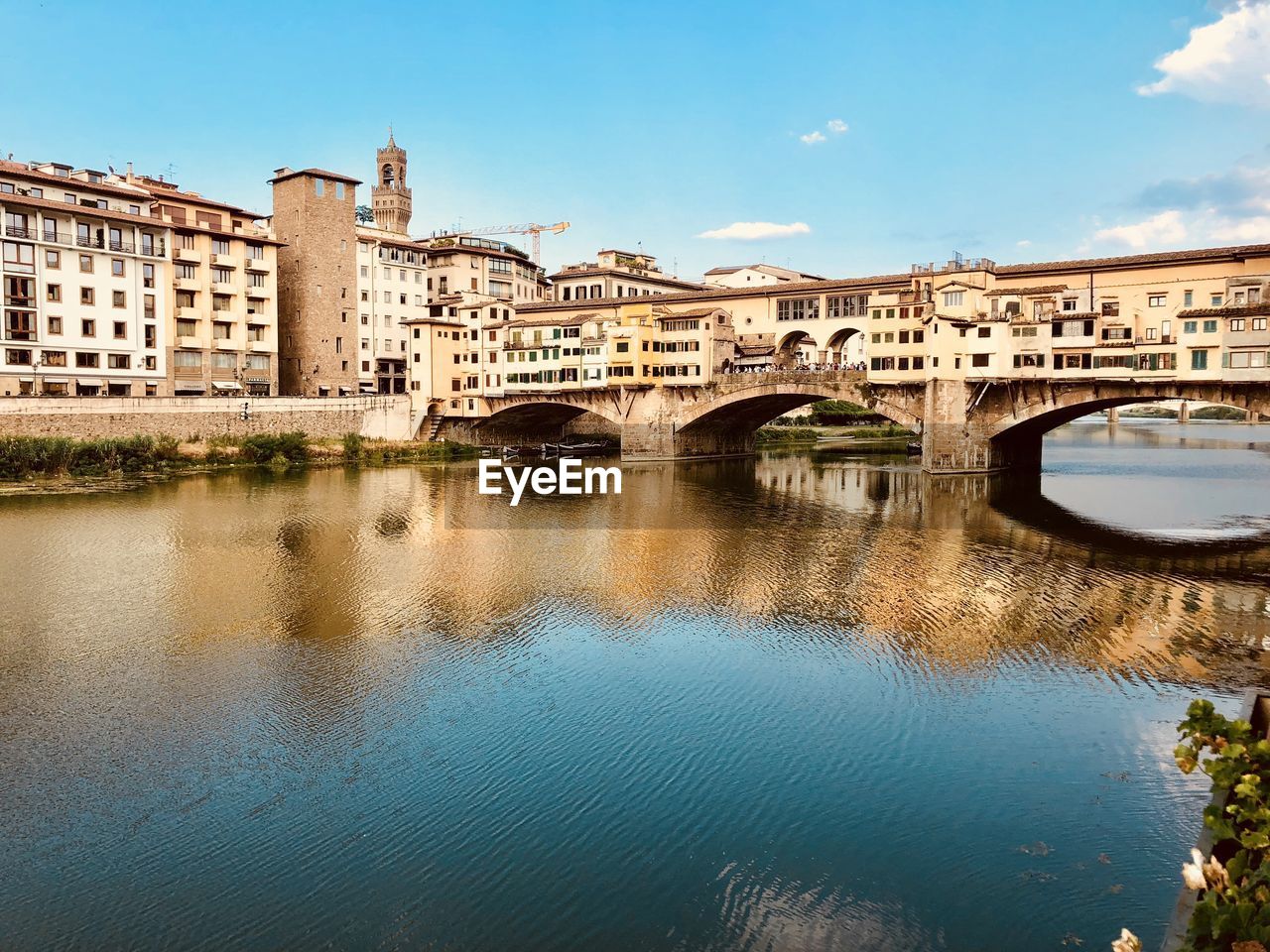 Arch bridge over river in city against sky