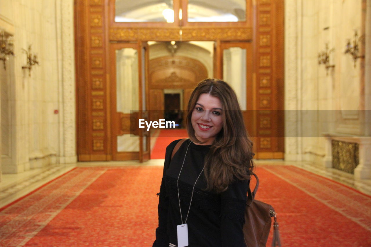 Portrait of young woman smiling while standing in building