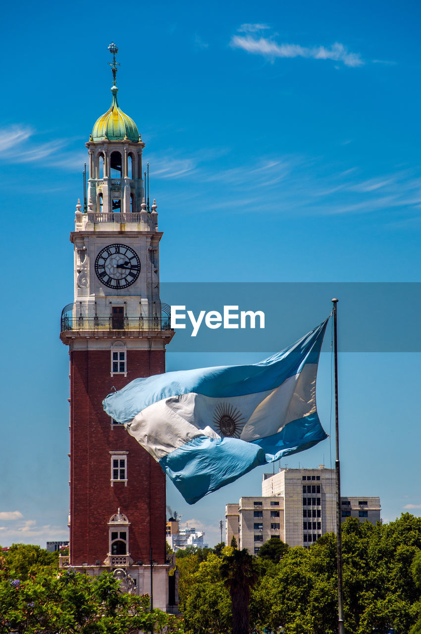 Argentinian flag waving in front of torre monumental against sky