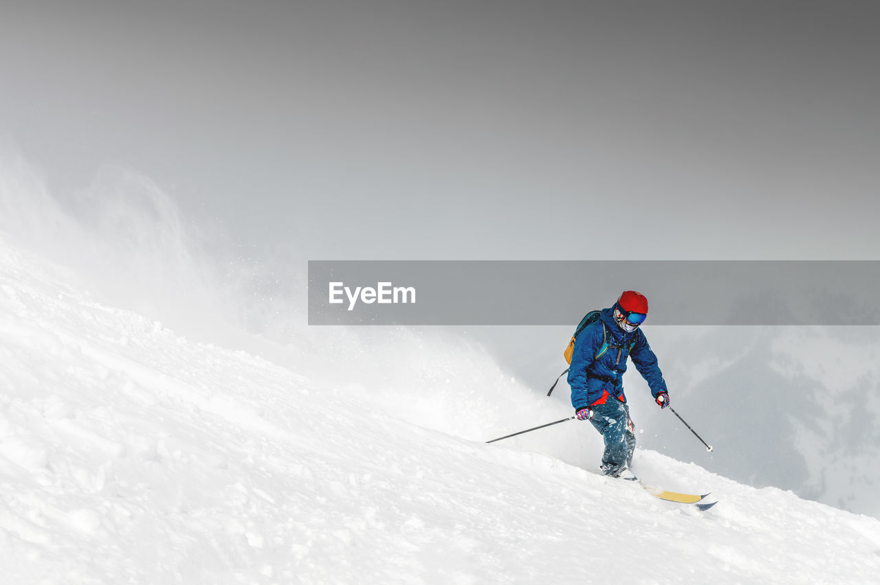 Skiing, skier, frisky - freeride, a man is stylishly skiing on a snowy slope with snow dust plume