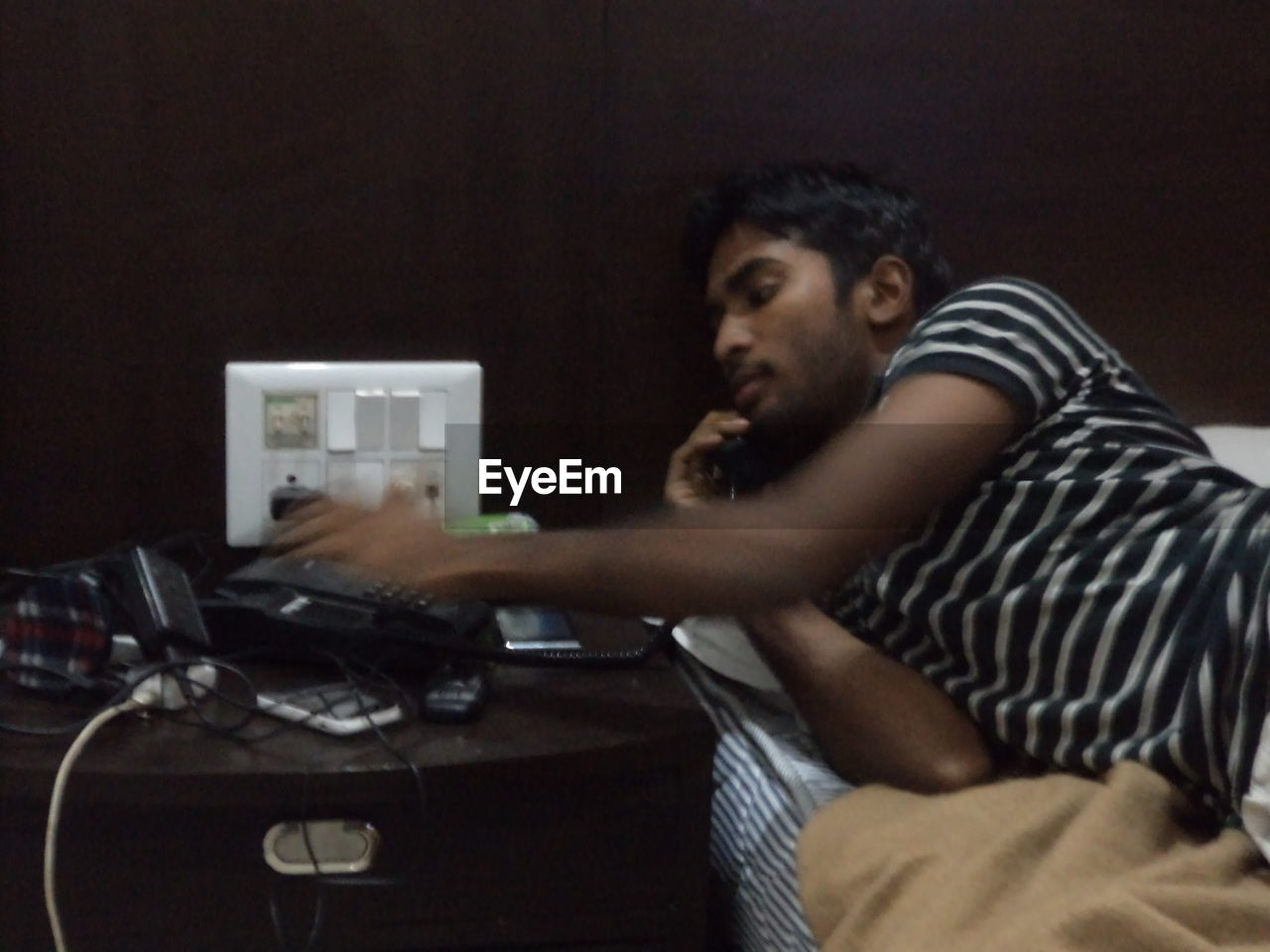 SIDE VIEW OF YOUNG MAN SITTING AT HOME