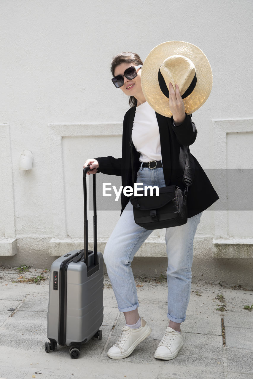 Young brunette girl in glasses with a suitcase goes on vacation,