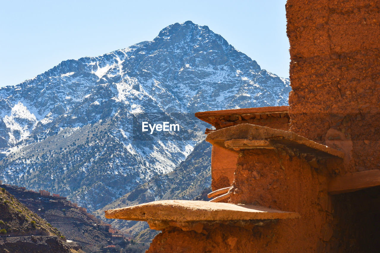 SNOW COVERED ROCK BY BUILDINGS AGAINST SKY