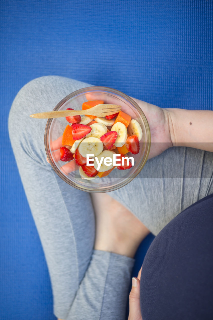 Low section of woman with fruits in bowl